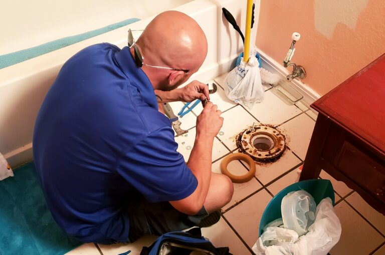 Bald Repairman sitting on floor installing new toilet in the bathroom in home remodeling of condo.